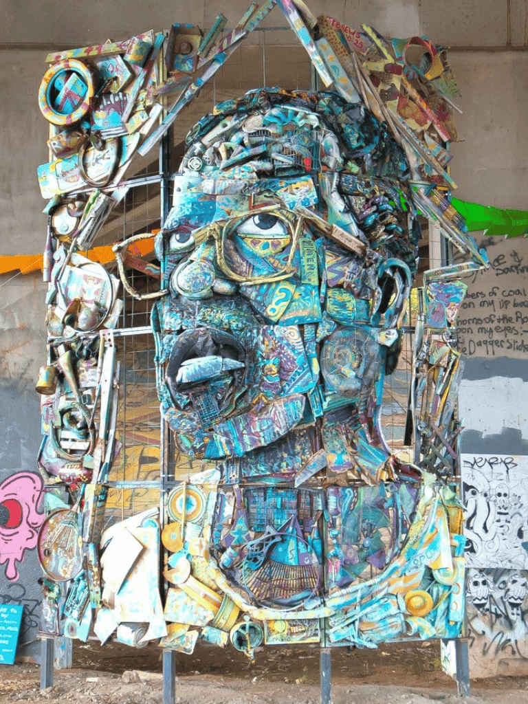 Colorful metal portrait sculpture of a man with glasses, showcasing urban art and street culture.