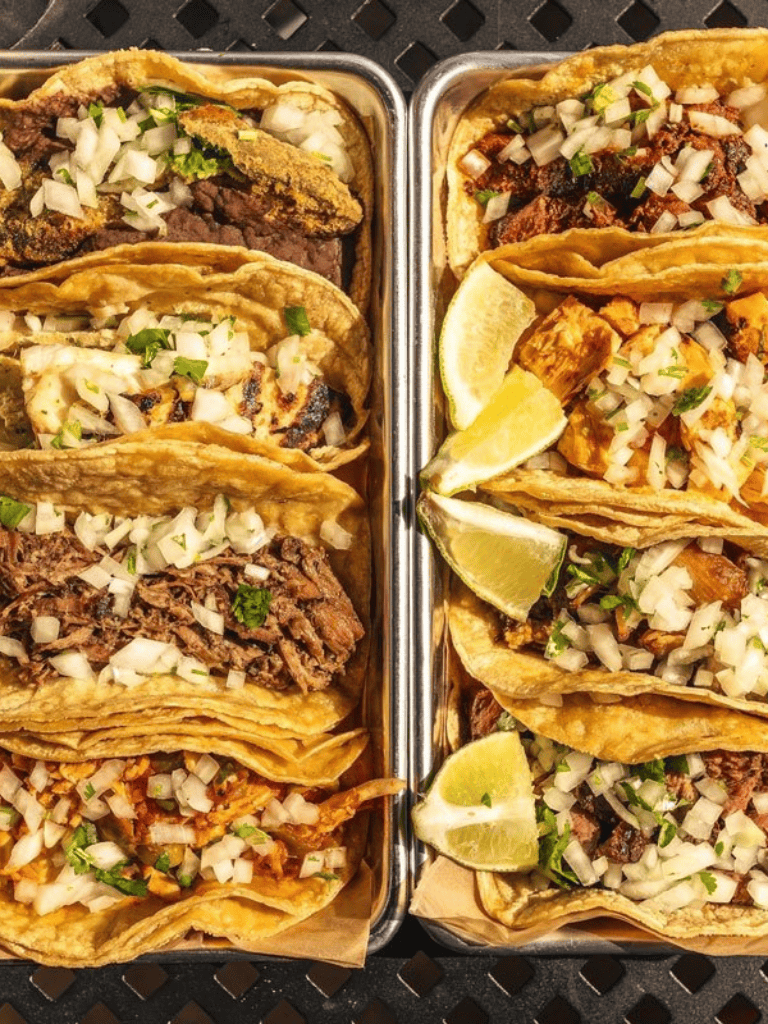 Tender beef and flavorful chicken tacos with fresh chopped onions, lime wedges, and crispy taco shells.