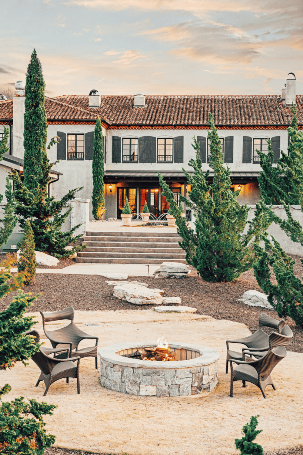 Luxurious Spanish-style estate with Mediterranean architecture and outdoor firepit area.