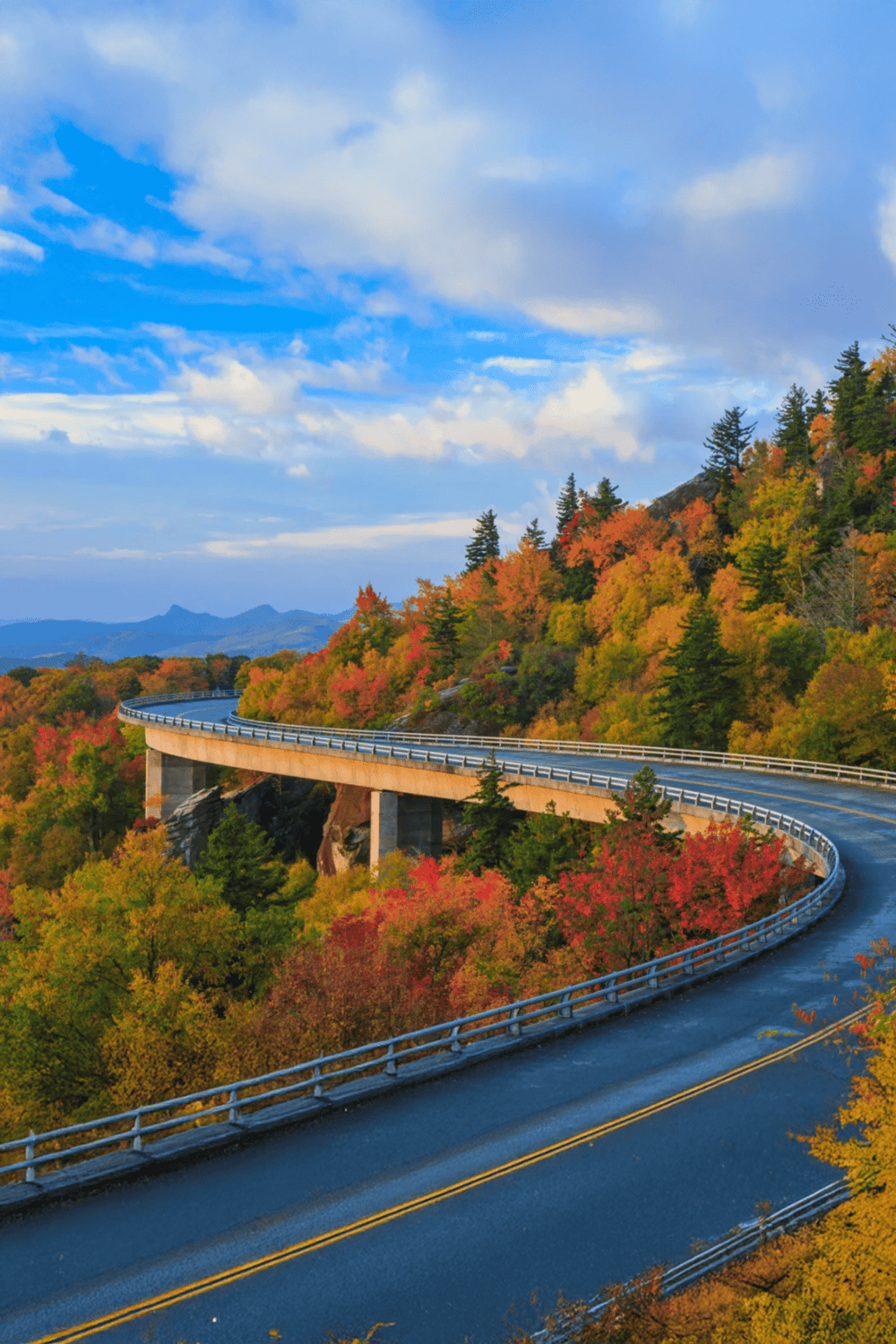 Vibrant autumn landscape with winding mountain road and colorful fall foliage scenery.