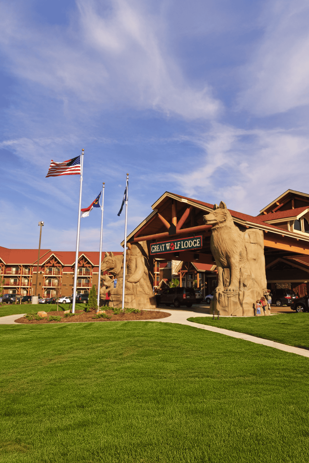 Flag of the United States and lodge entrance with bear sculptures for Great Wolf Lodge, a popular family-friendly destination.