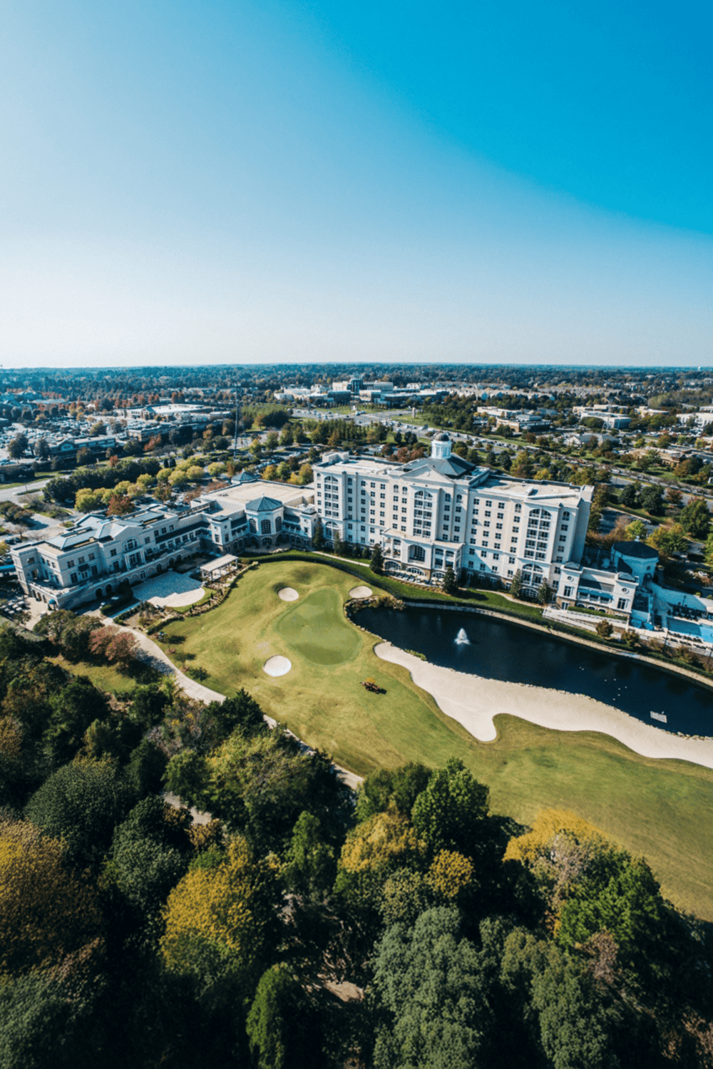 Luxury hotel with golf course and scenic pond, located in a vibrant cityscape.