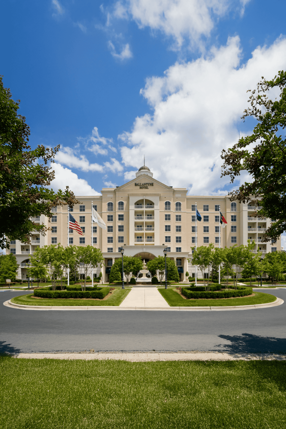 Elegant hotel exterior with lush landscaping and American flags, perfect for travel and accommodation keywords.