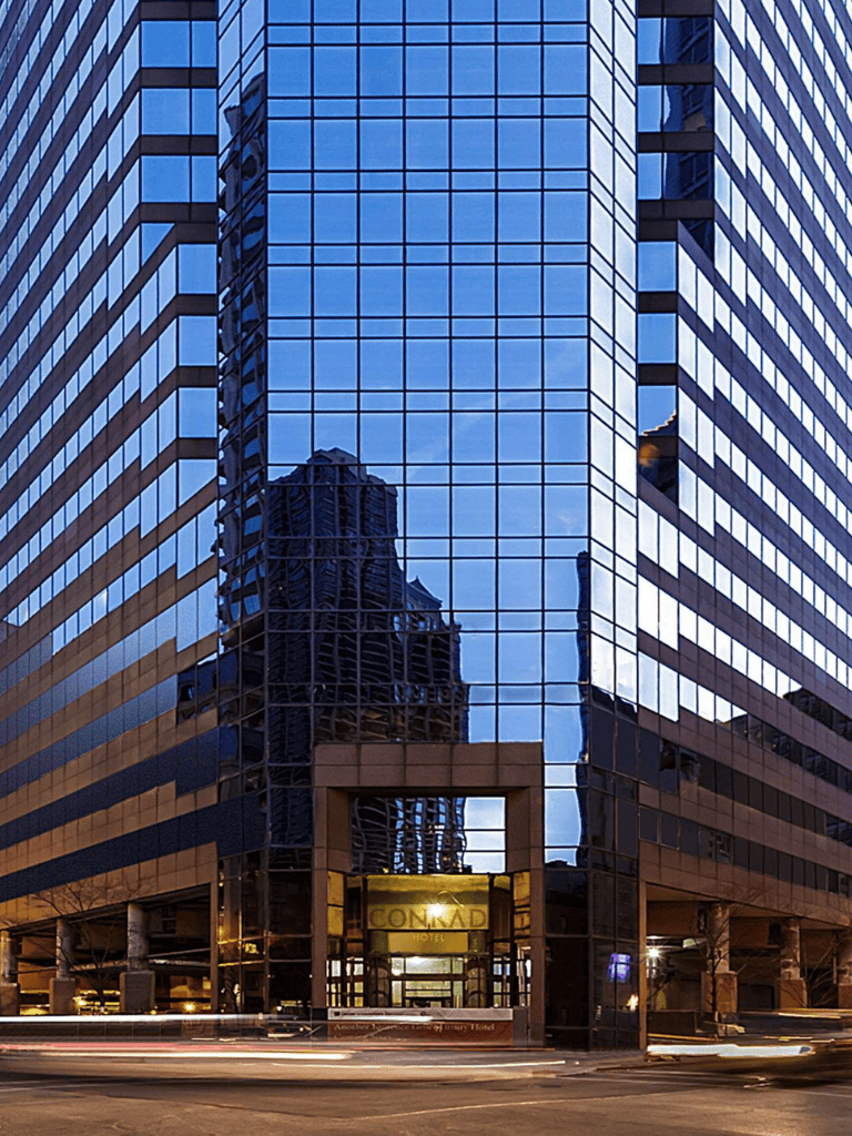 Modern glass skyscraper reflecting cityscape.