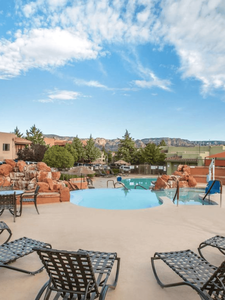 Relaxing outdoor pool with hot tub surrounded by rock features and lounge chairs - QuestForDirections.