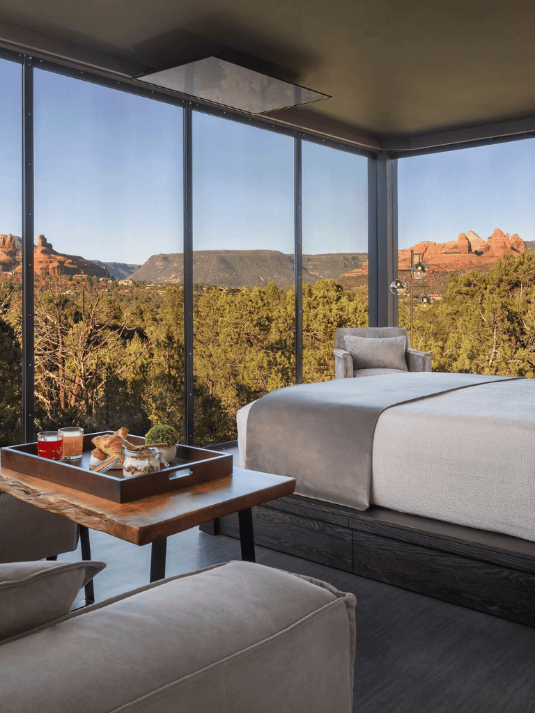 Serene mountain view from modern hotel room with large windows, cozy bed, and stylish decor in Sedona, Arizona.