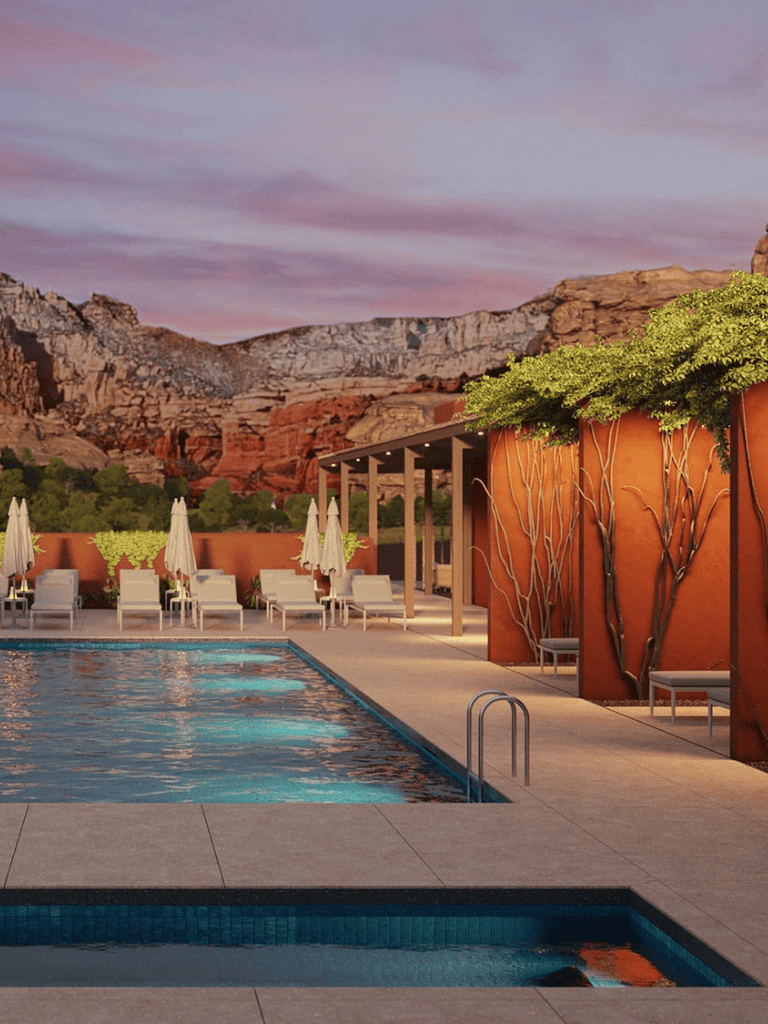 Serene outdoor hotel pool with mountain views, lounge chairs, umbrellas, and lush greenery at sunset.