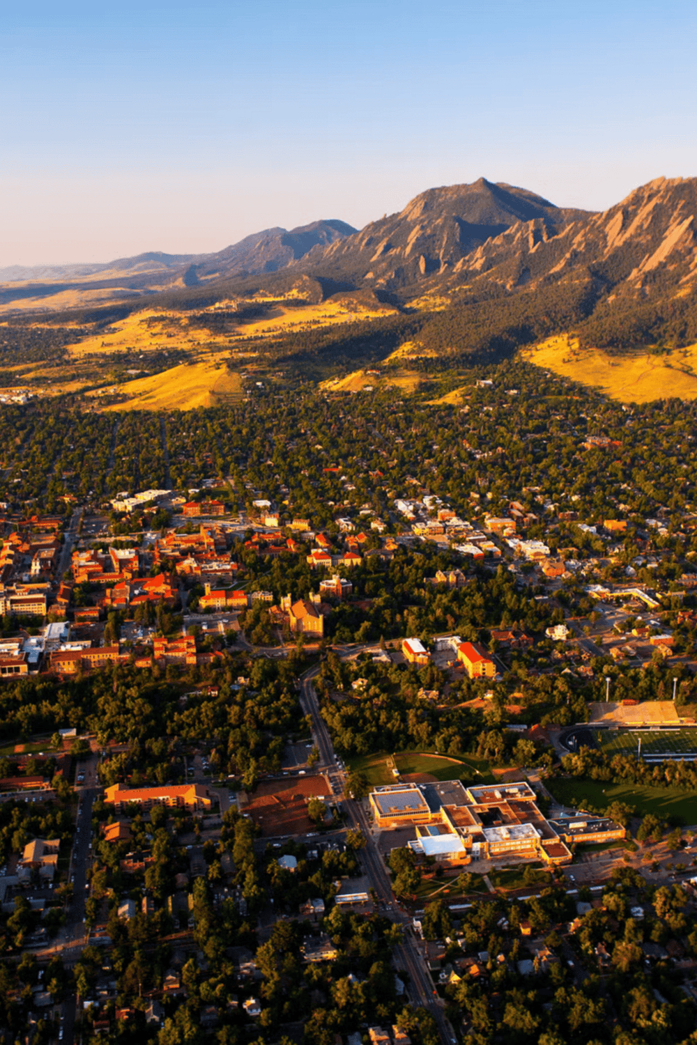 Vibrant aerial view of a city surrounded by lush greenery and mountainous landscape, highlighting scenic beauty and urban development.