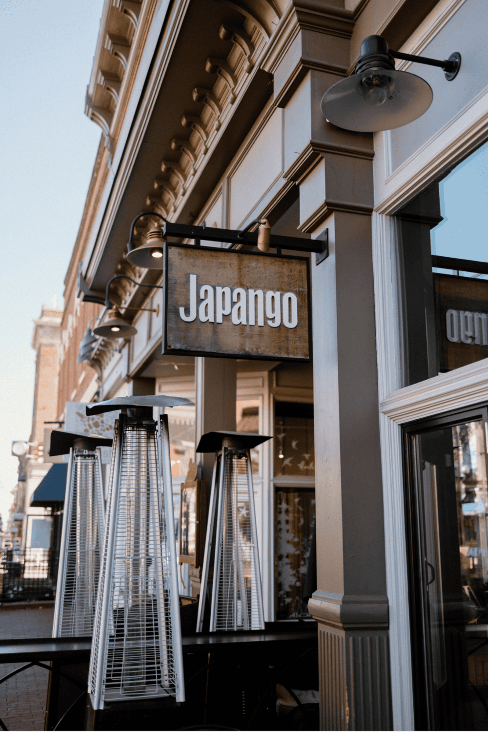 Outdoor Japanese restaurant sign with heaters and classic architecture.