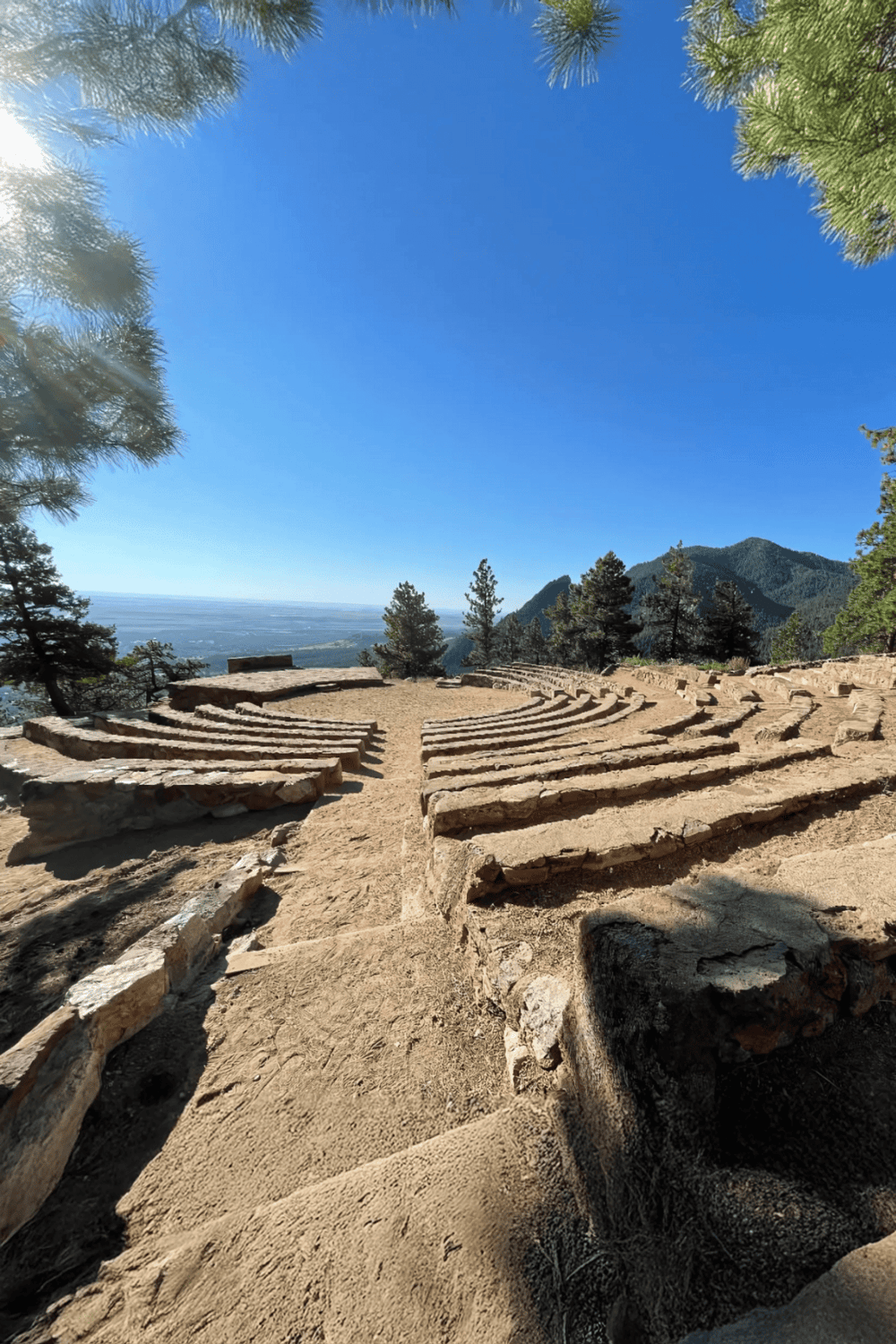 Ancient amphitheater in the mountains with scenic view and clear blue sky.