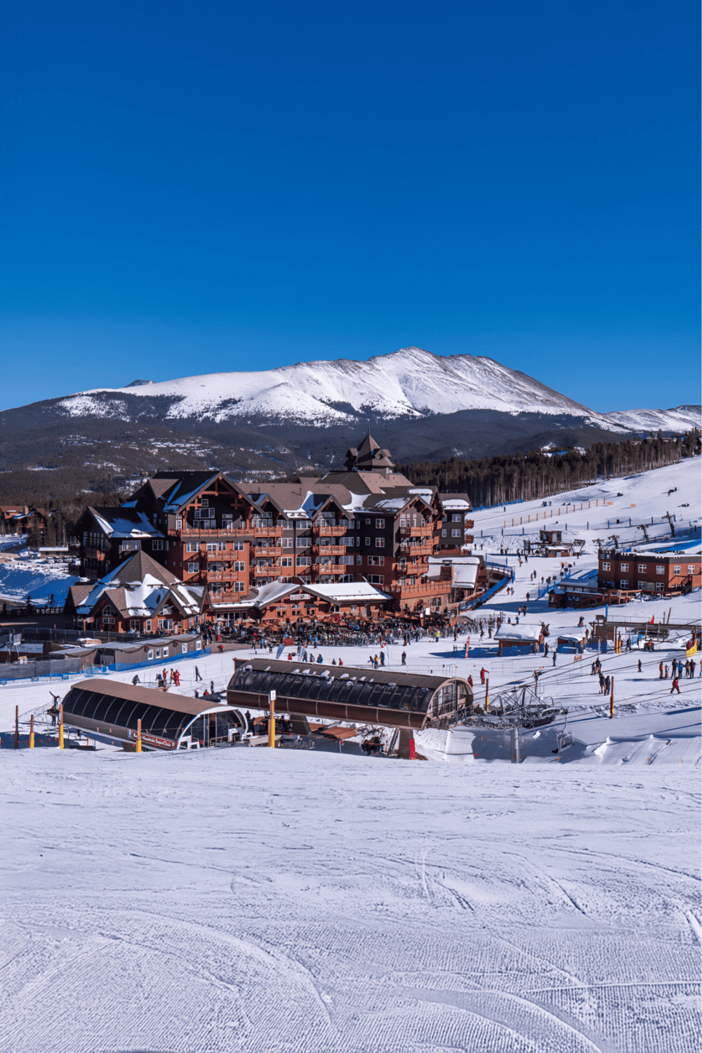 Snowy mountain lodge at a ski resort with ski lifts and winter activities.