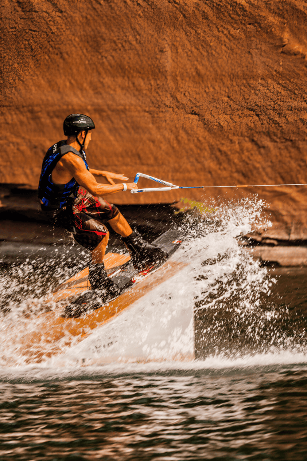 1. Man wakeboarding on water with rocky canyon background.