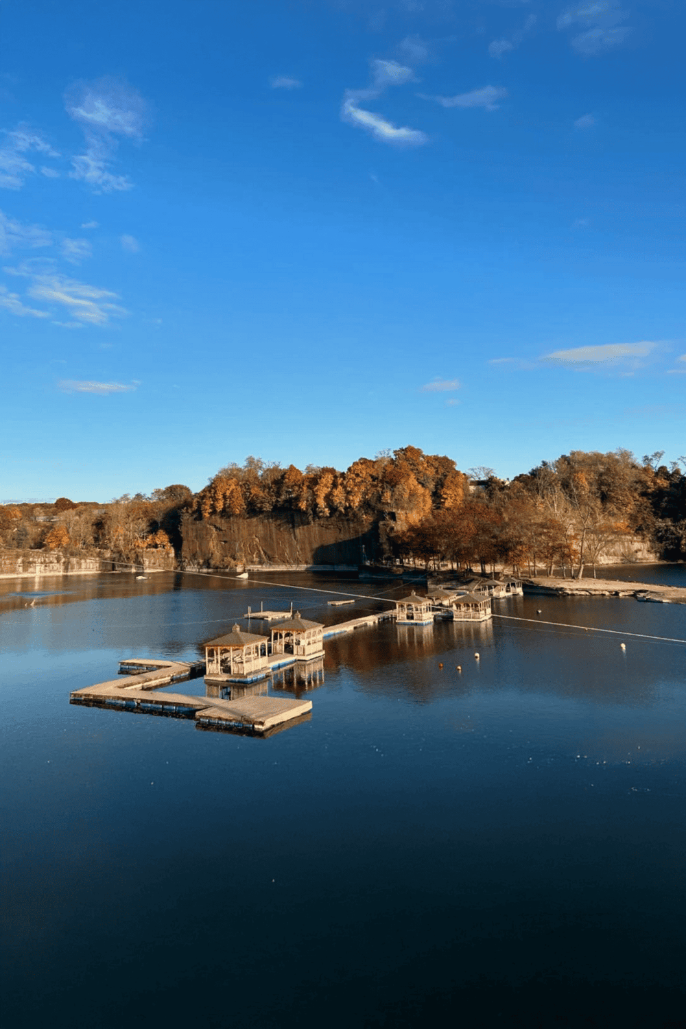 Serene lake with docks and autumn trees in the background, scenic outdoor location for relaxation and recreation.