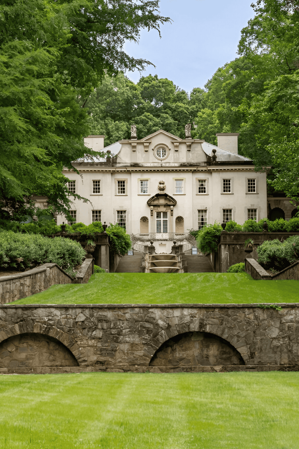 Chateau surrounded by greenery, classic architecture with lush lawn, elegant historic estate.