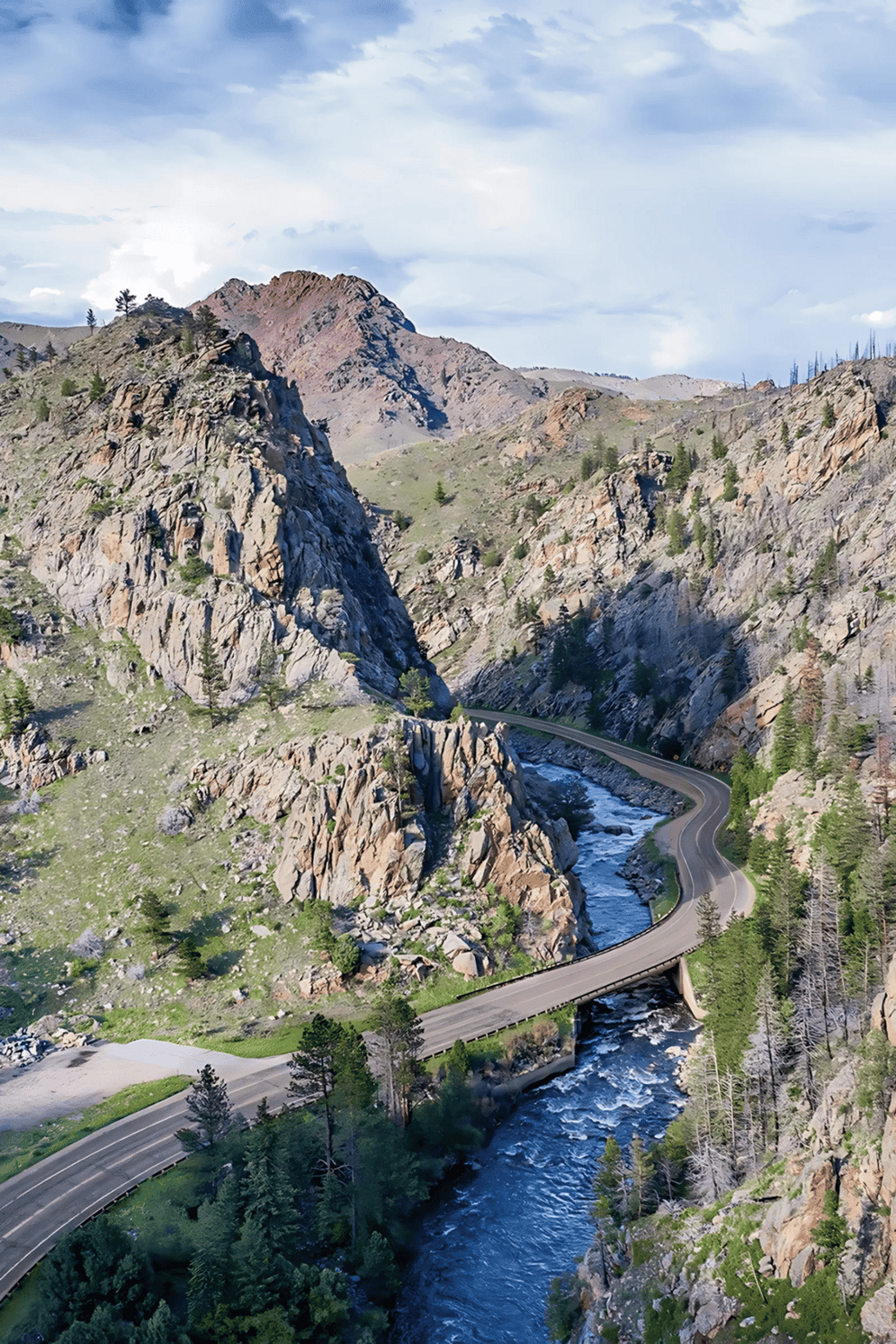 Serene mountain landscape with winding road and river, ideal for outdoor adventure and nature exploration.