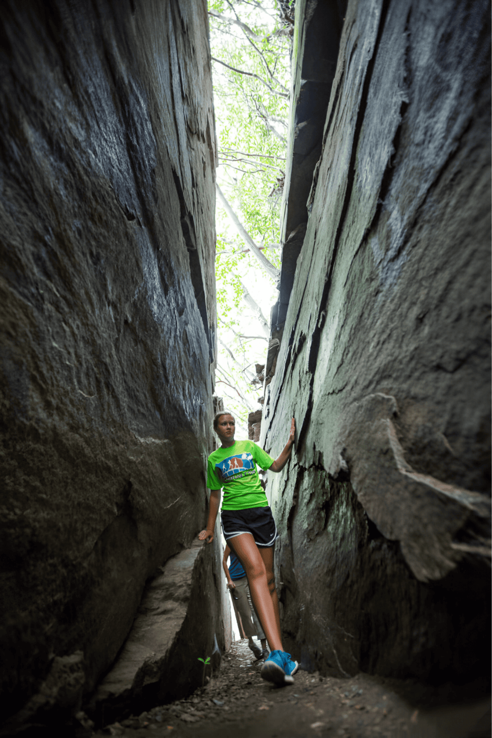 - Deep rock crevice with person exploring narrow canyon walls.