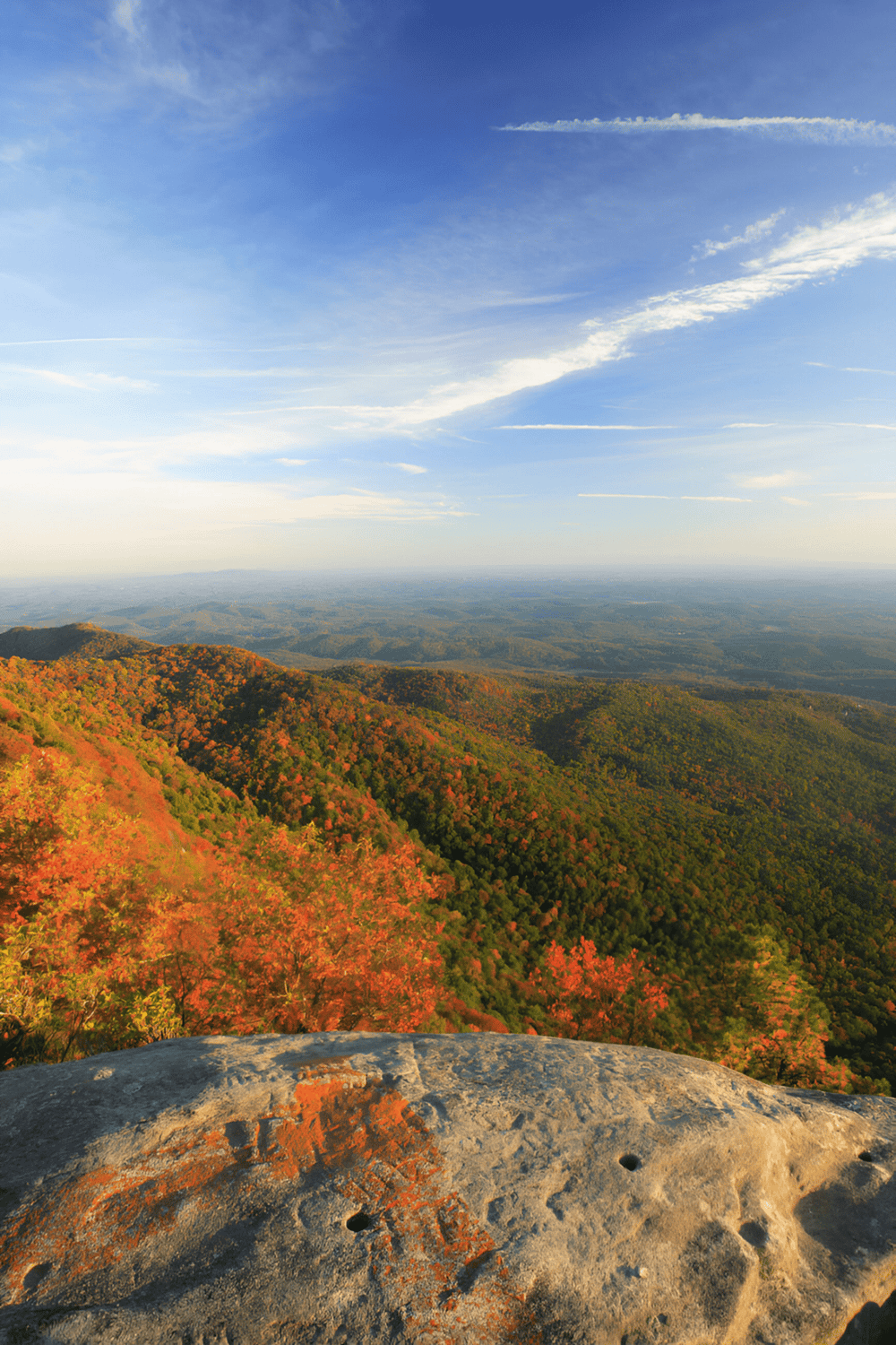 Vast mountain landscape with colorful autumn foliage and blue sky, scenic outdoor views, hiking, nature exploration.