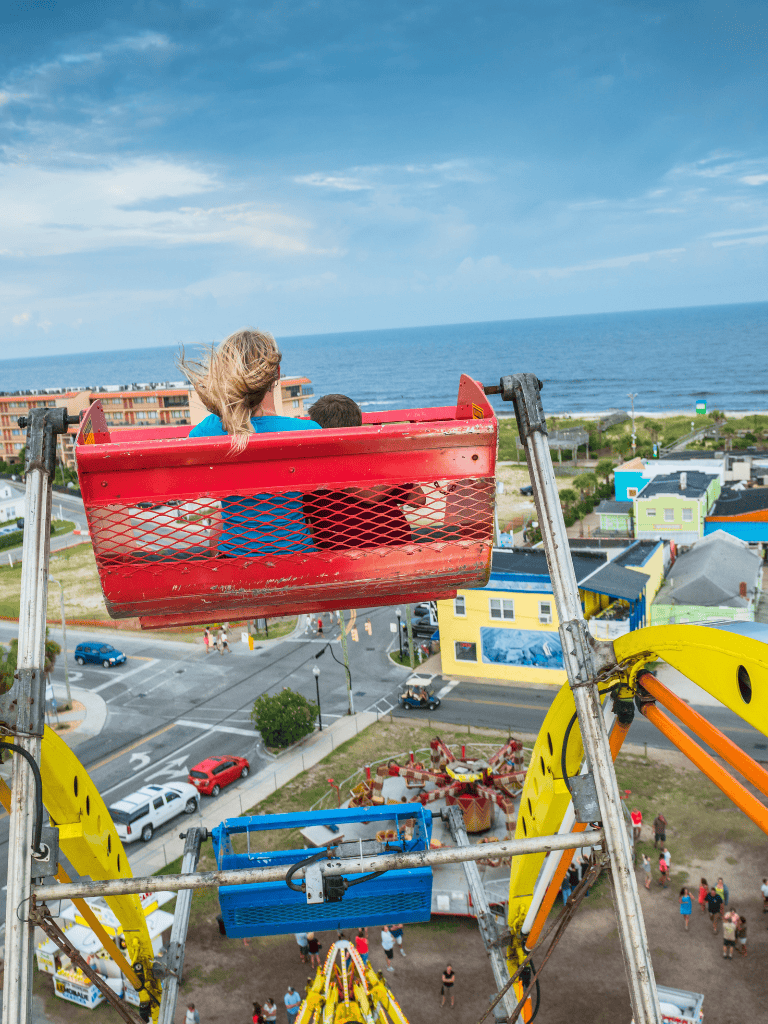 Bright ferris wheel ride overlooking colorful coastal town and ocean horizon for fun family adventure.