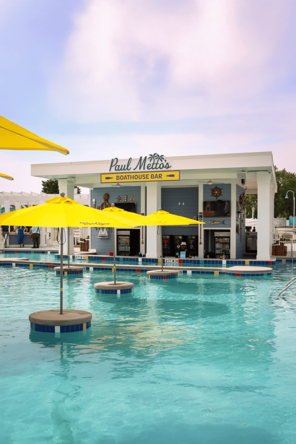 Outdoor pool at Quest for Directions with boathouse bar and vibrant yellow umbrellas.