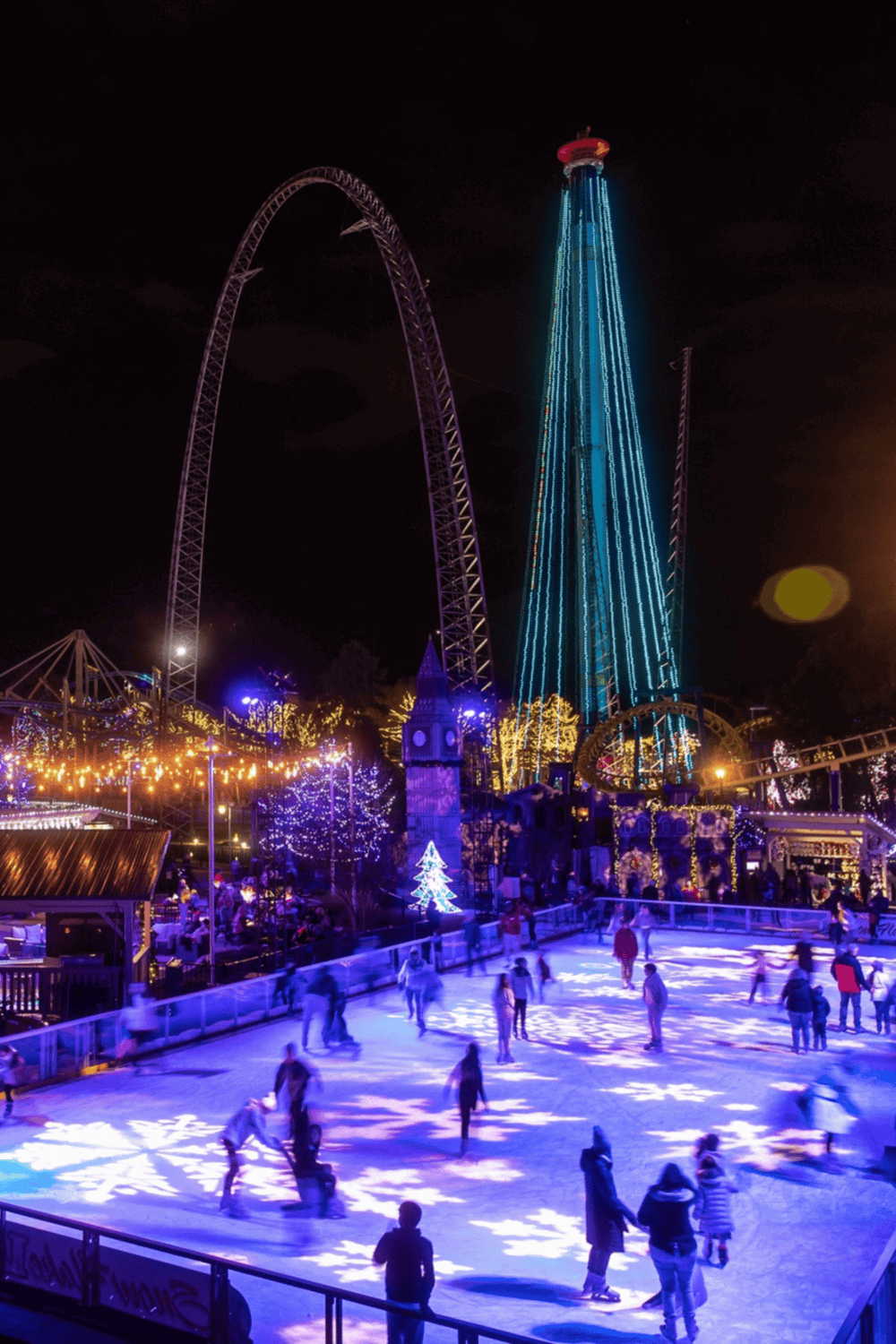 Bright amusement park night scene with illuminated roller coaster and ice skating rink, perfect for families and thrill-seekers.