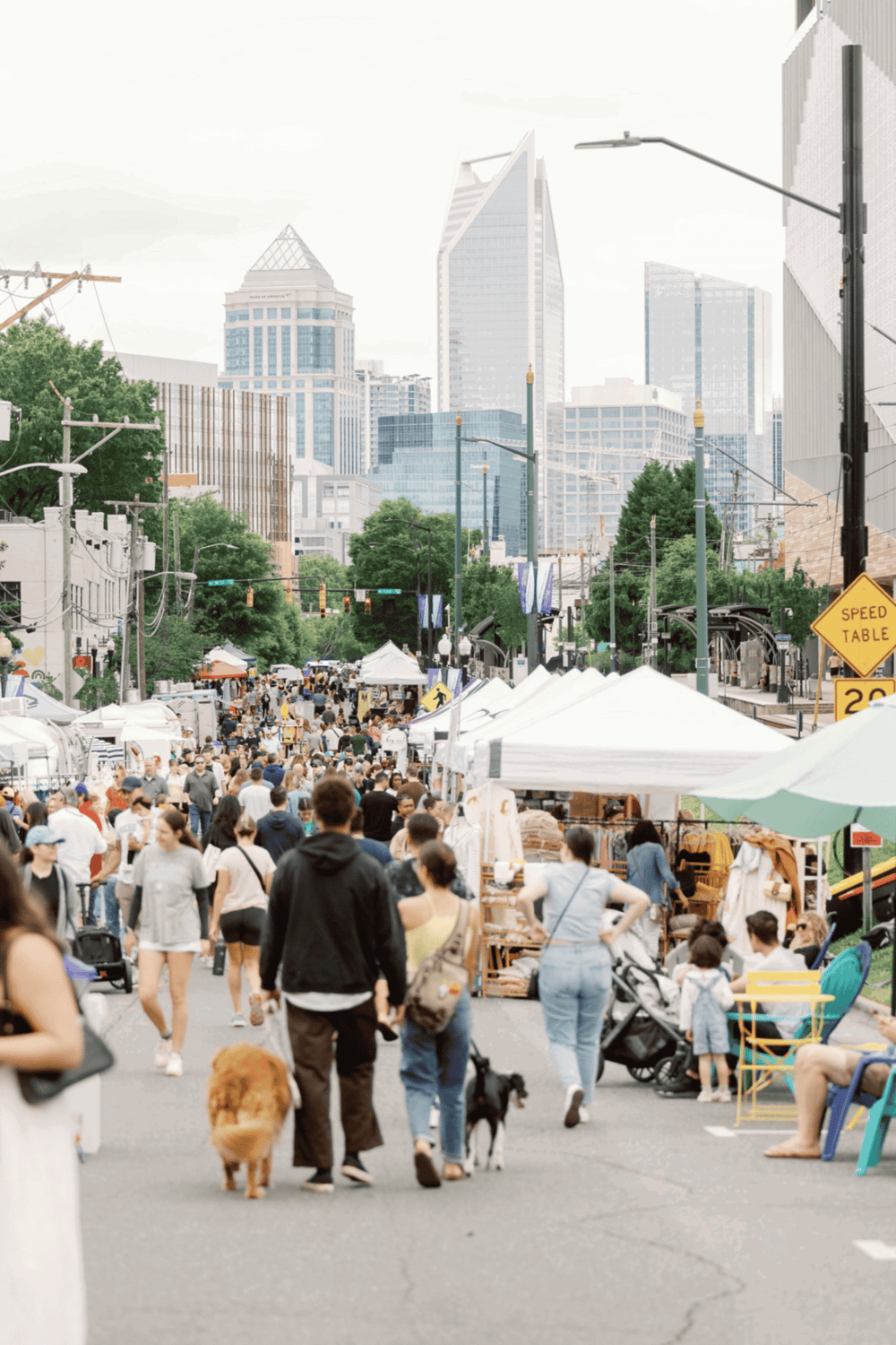 Vibrant outdoor street market in a bustling city with modern skyscrapers.