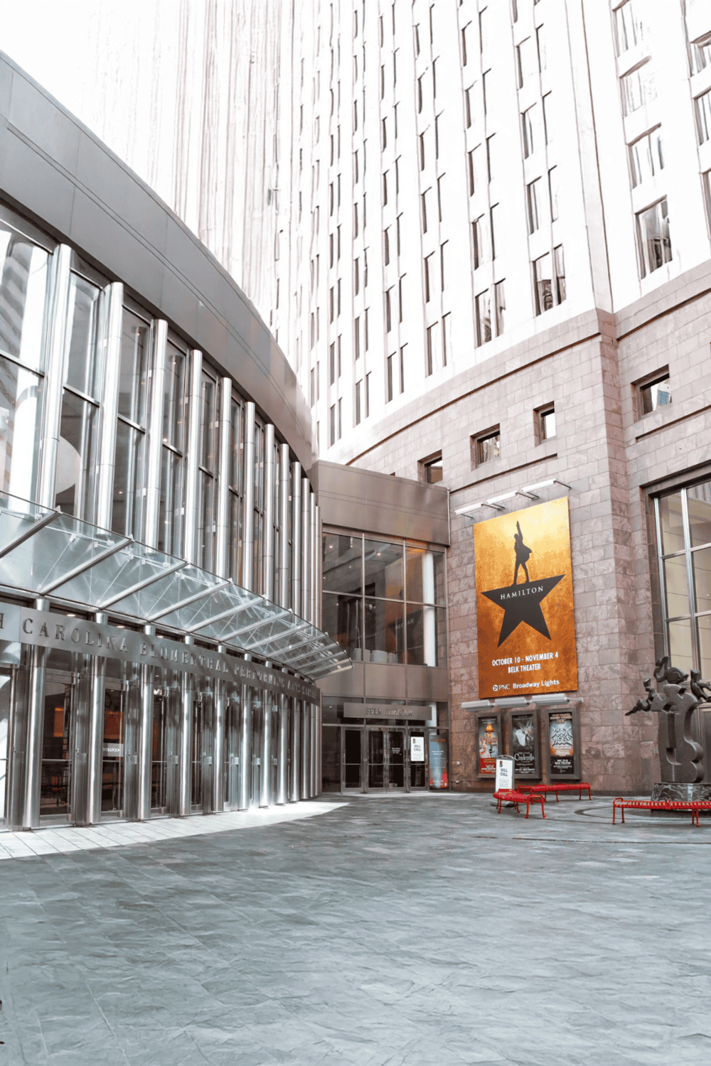 Modern urban building entrance with glass and steel architecture, home to theatrical performances and entertainment venues.