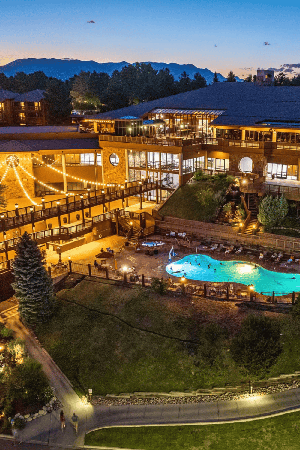 Relaxing mountain resort with swimming pool, outdoor seating, and scenic mountain views at dusk.