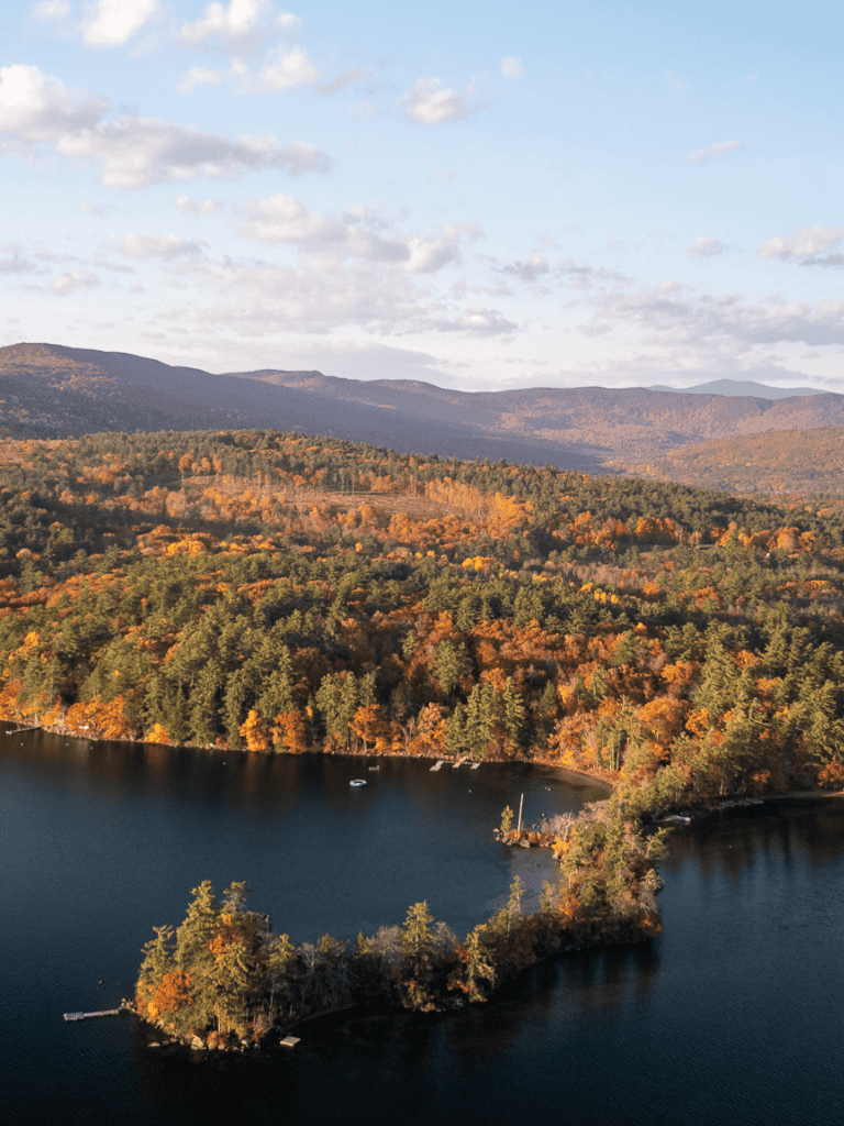 Rich fall landscape of mountains, lake, and colorful trees in autumn, scenic outdoor location for nature lovers.