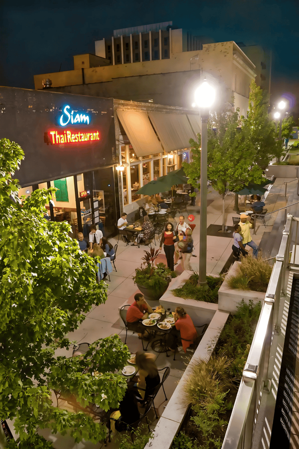 Elegant outdoor dining at Siam Thai Restaurant at night, with vibrant street view and lively atmosphere.
