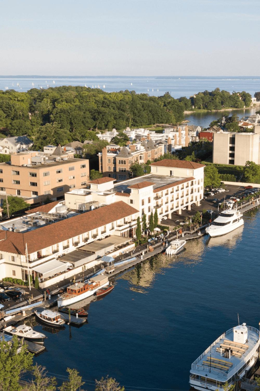Harbor view of QuestForDirections waterfront hotel with boats and lush green landscape.