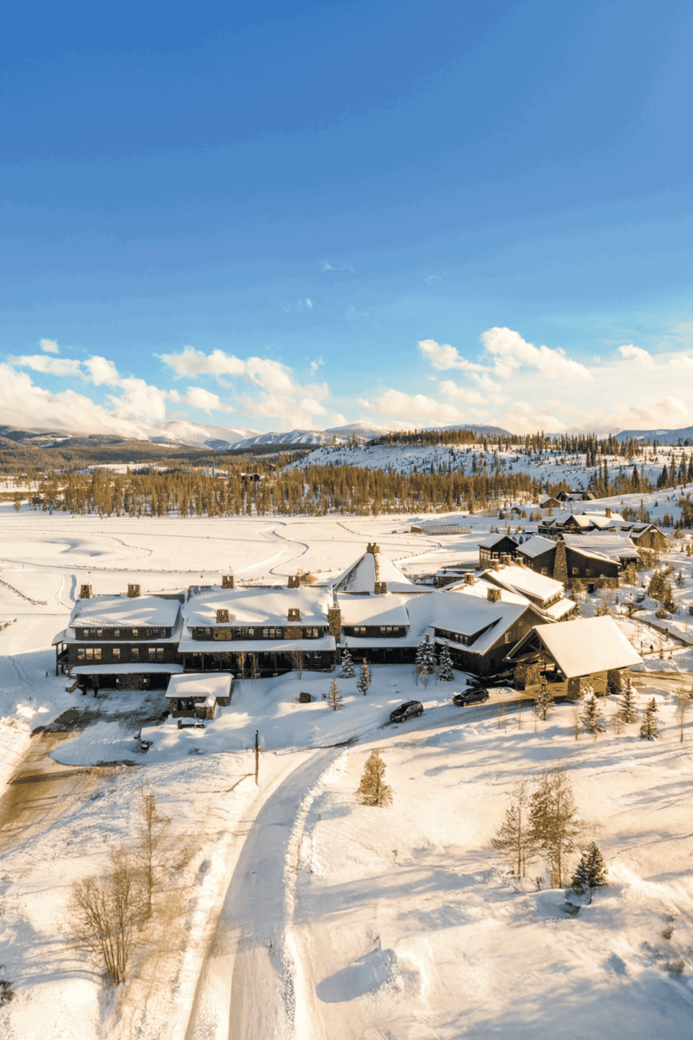 Snow-covered mountain lodge with scenic winter landscape and clear blue sky.