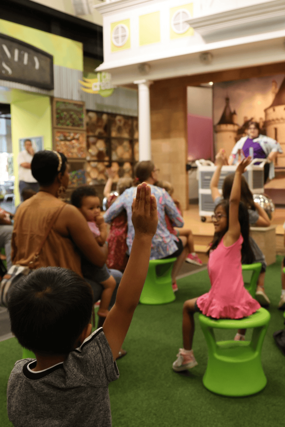 Kids asking questions and participating during storytime at a children's museum.