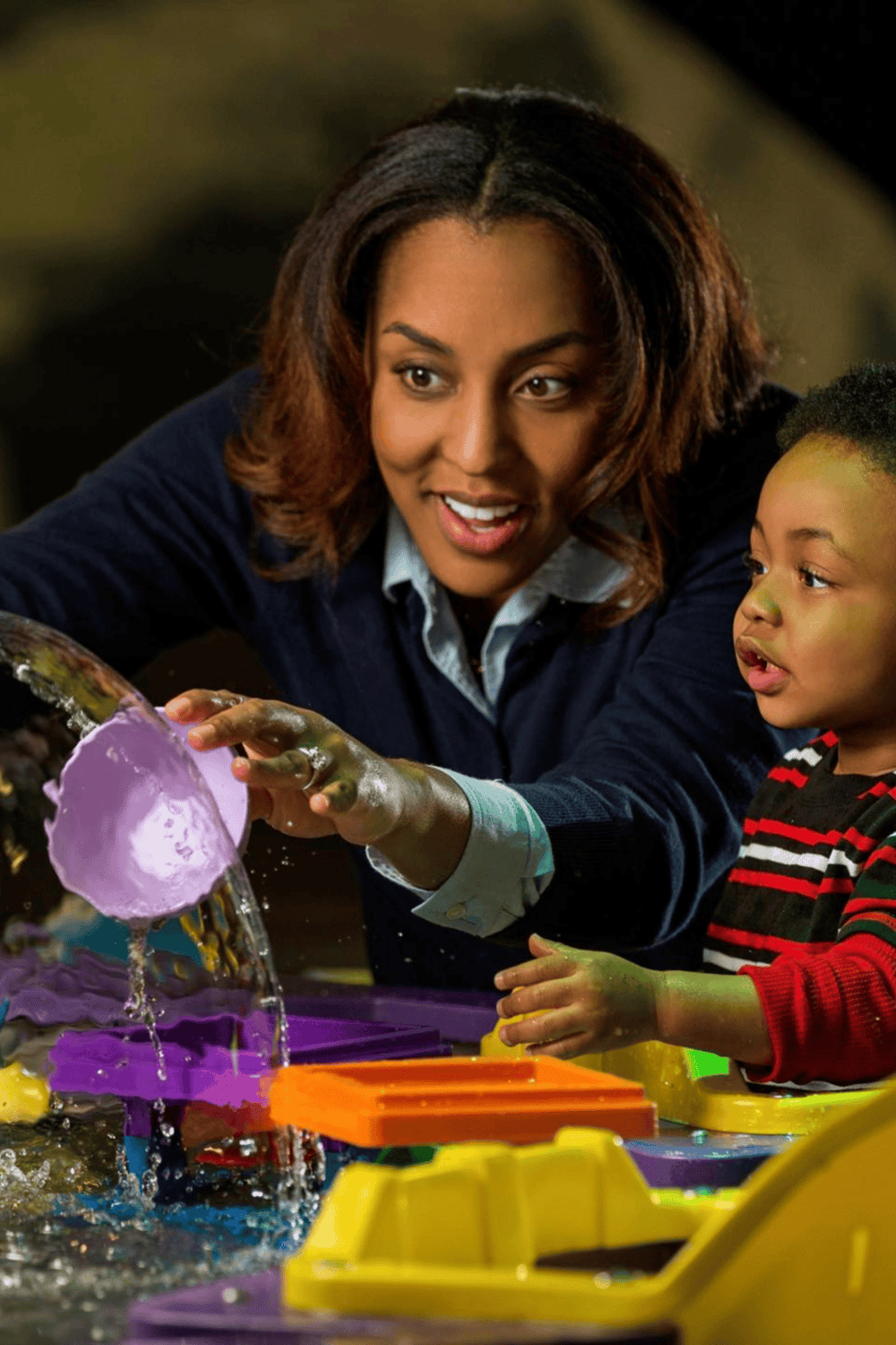 Bright African American woman and child engaging in creative science activity with colorful slime and water.