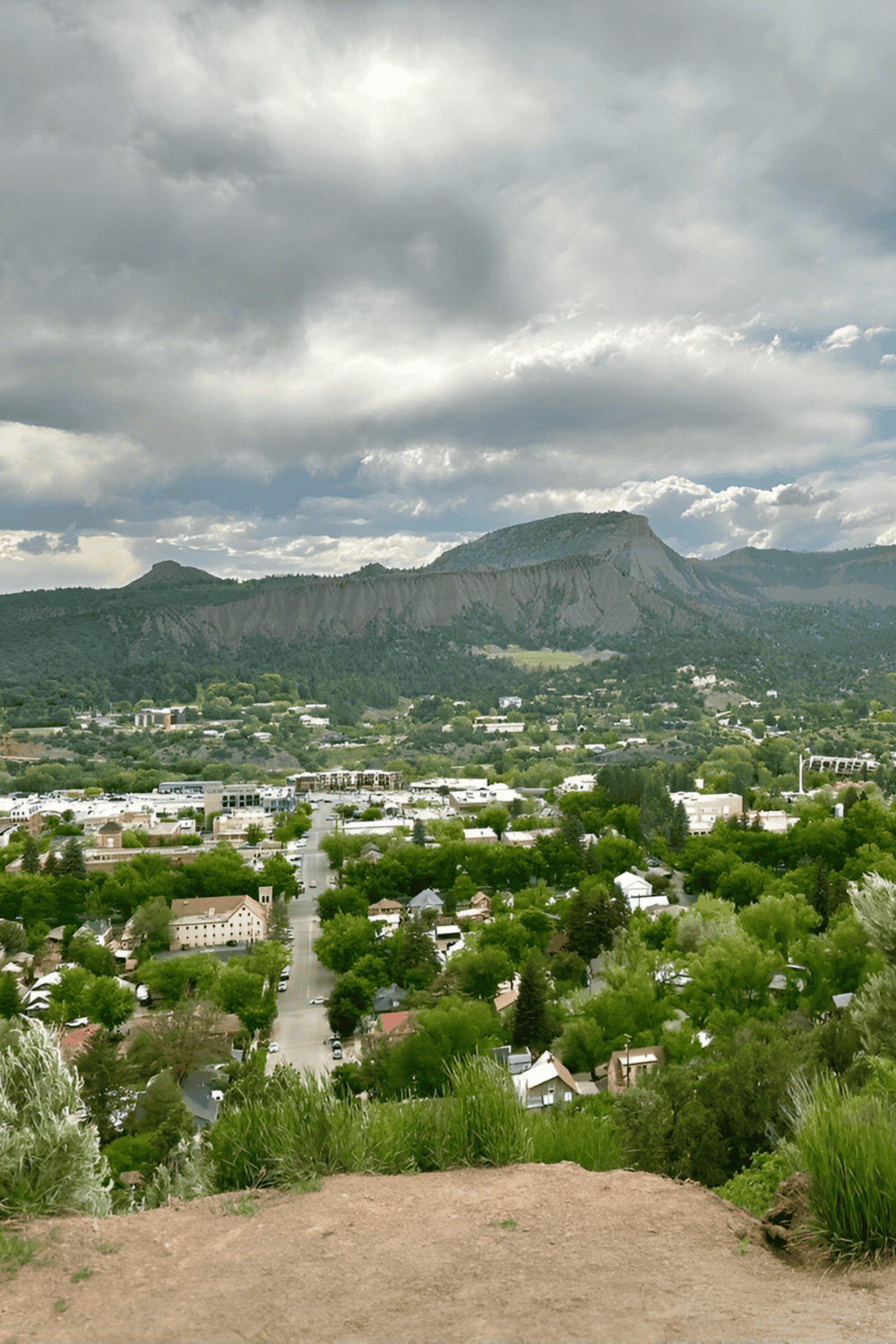 Vivid cityscape view with mountains, lush greenery, and cloudy sky, ideal for exploration and travel planning.