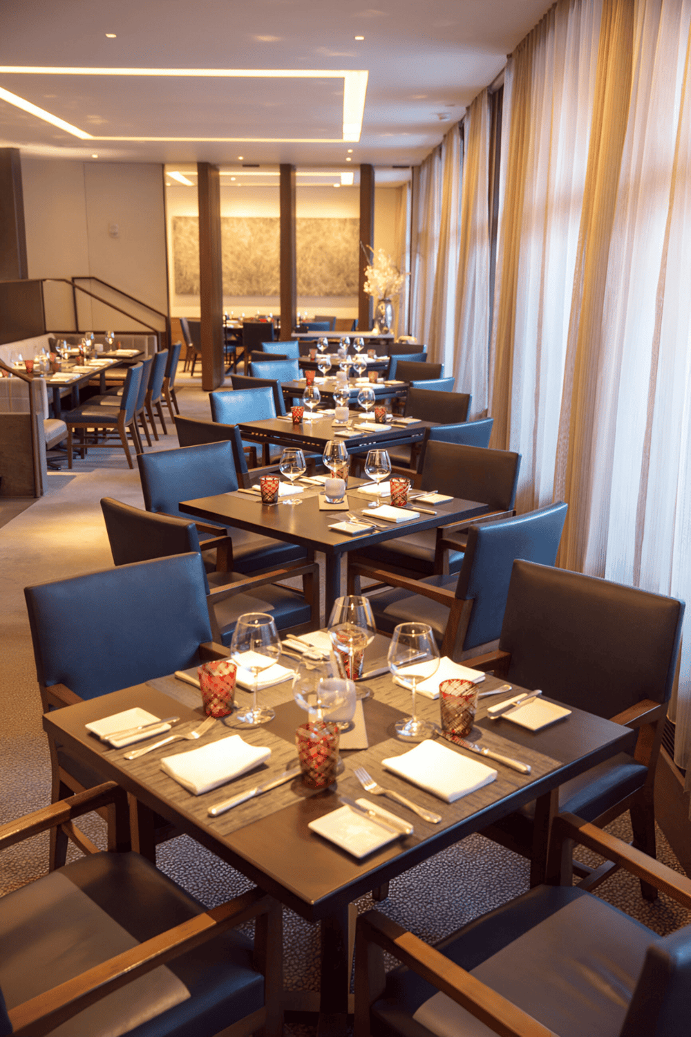 Elegant restaurant dining room with modern decor, tableware, and ambient lighting.