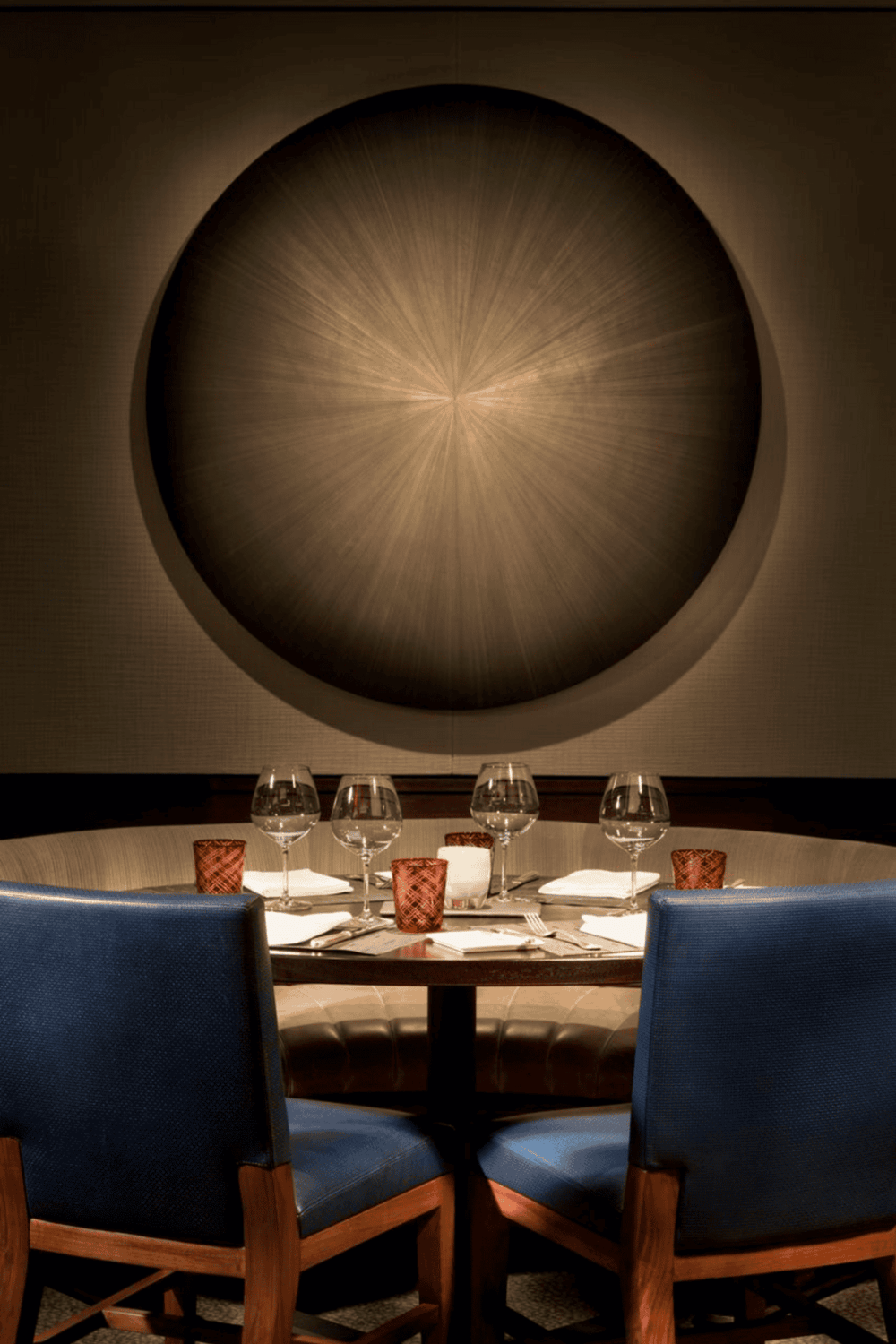 Modern restaurant table set with wine glasses, candles, and elegant decor for dining.