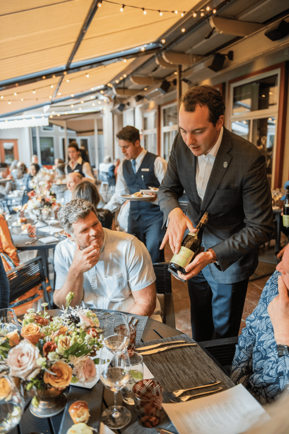 Elegant dinner at a restaurant with attentive staff and floral table settings, creating a sophisticated dining experience.