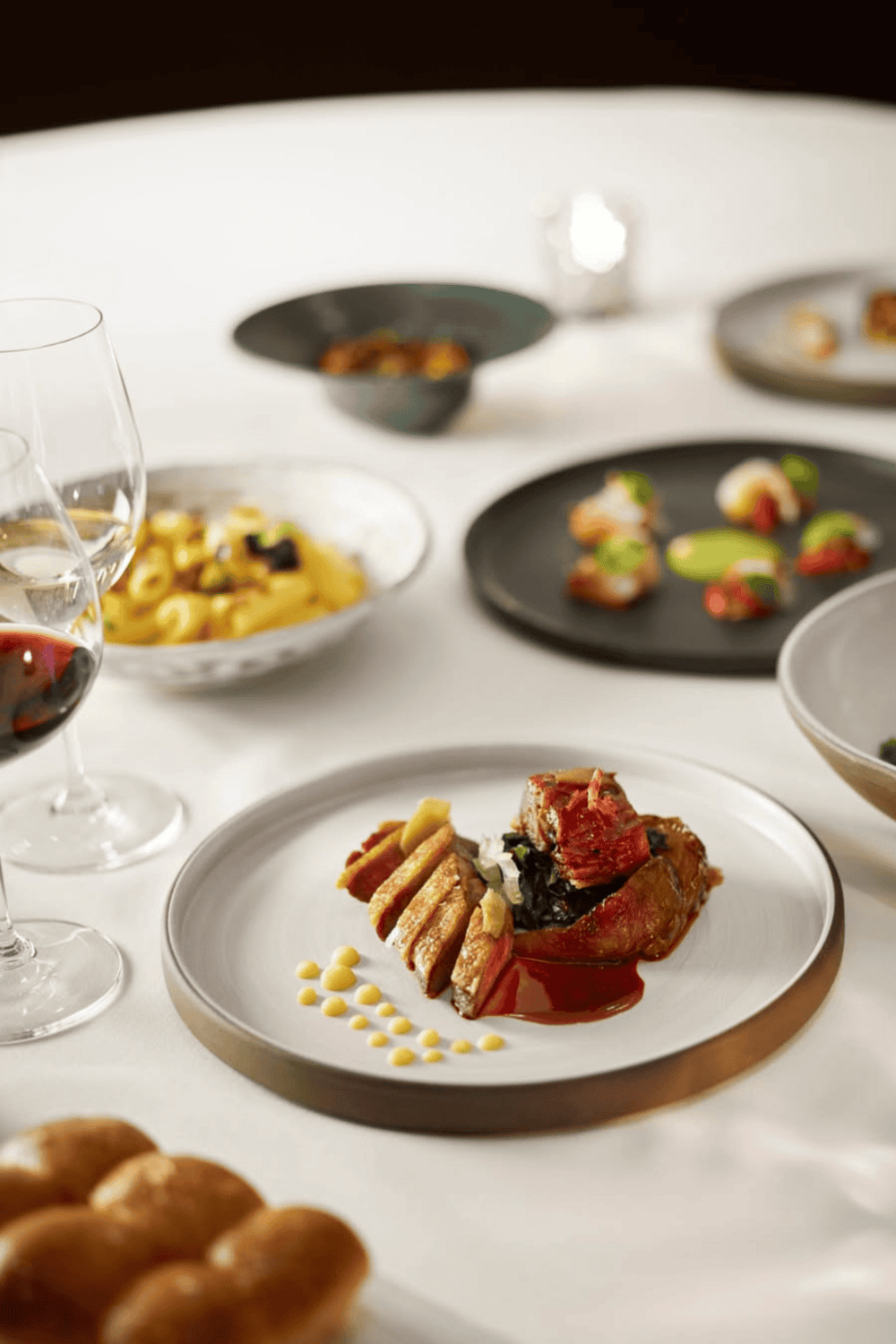 Gourmet plated dishes with wine glasses, fine dining presentation, elegant restaurant ambiance, QuestForDirections culinary experience.