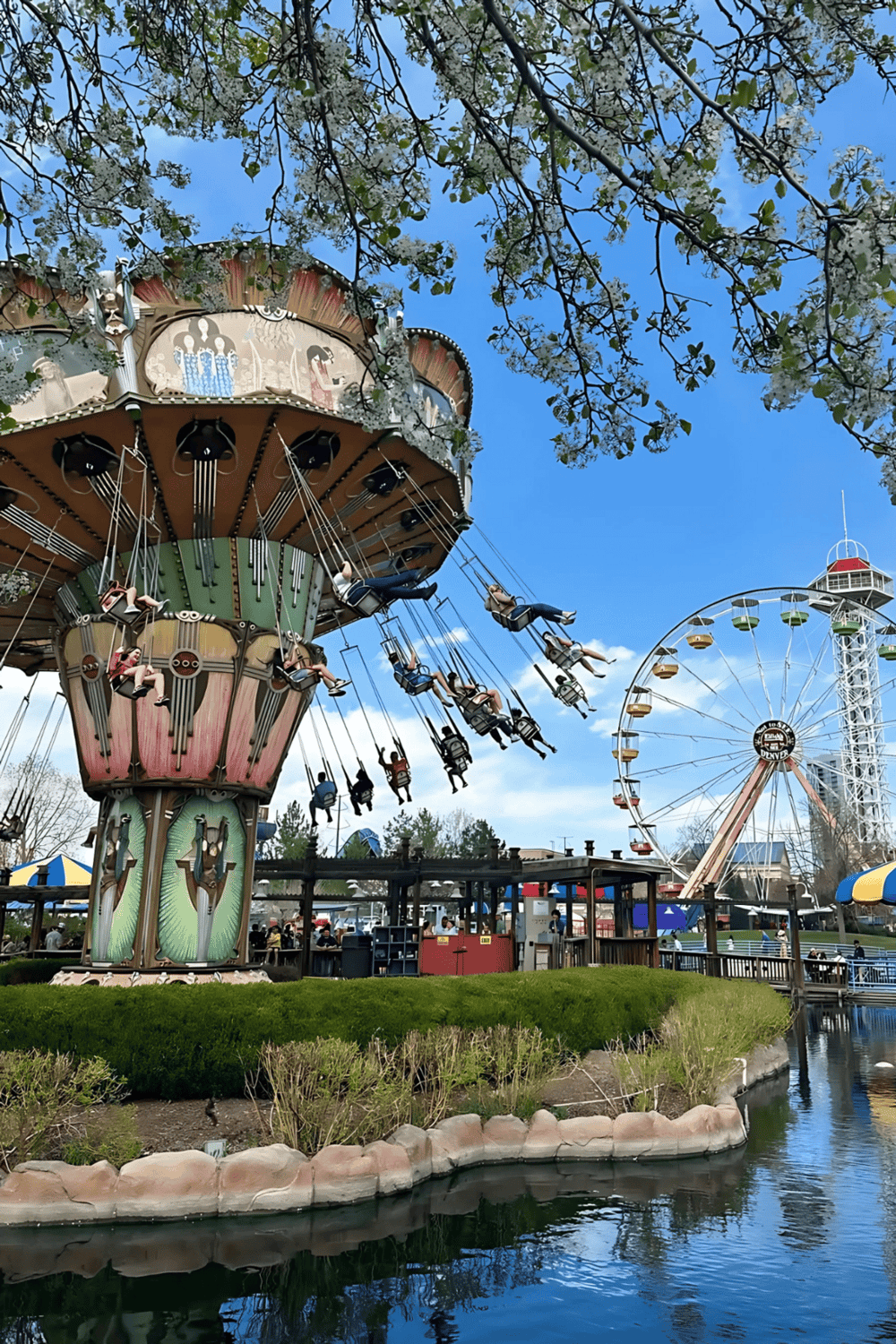 Colorful amusement park with a large swing ride and a Ferris wheel under a blue sky.