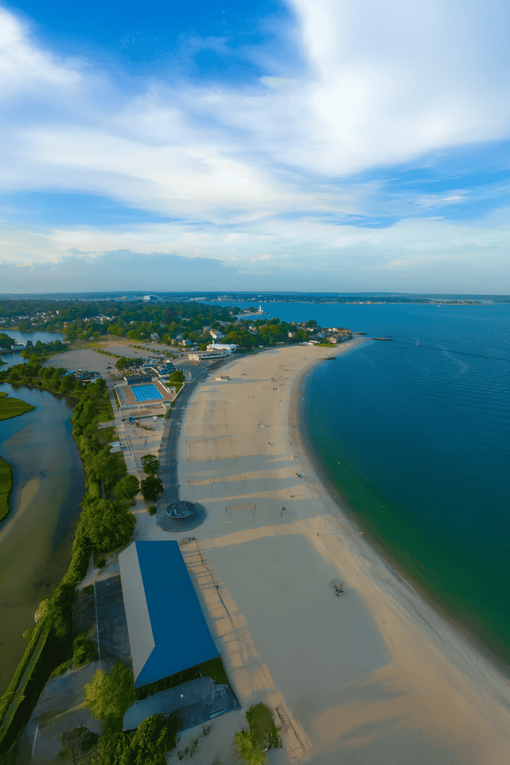 Beach and shoreline aerial view with scenic ocean, blue sky, and nearby park - ideal destination guide.