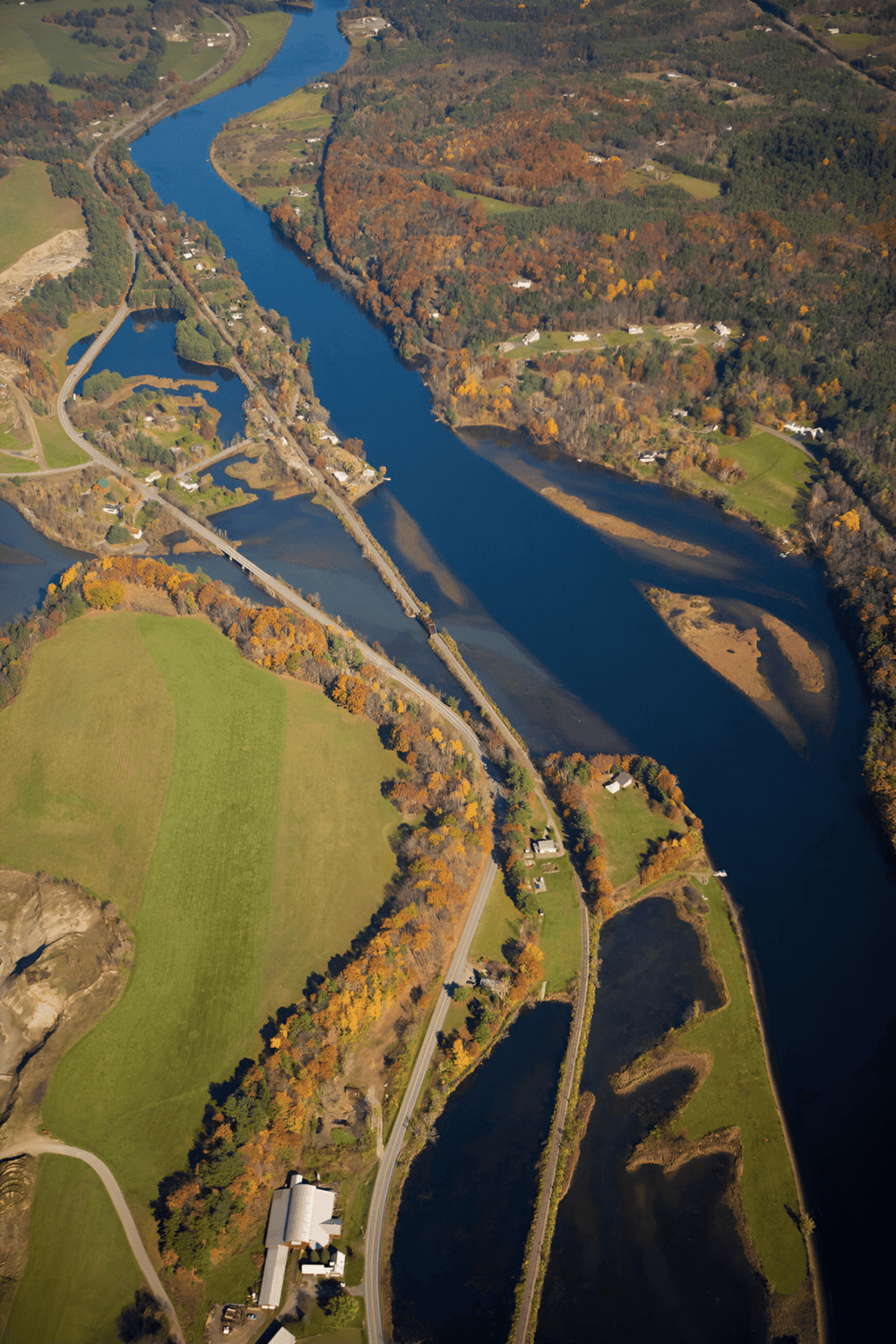 Aerial view of scenic river landscape with bridges and fall foliage, perfect for travel and navigation.