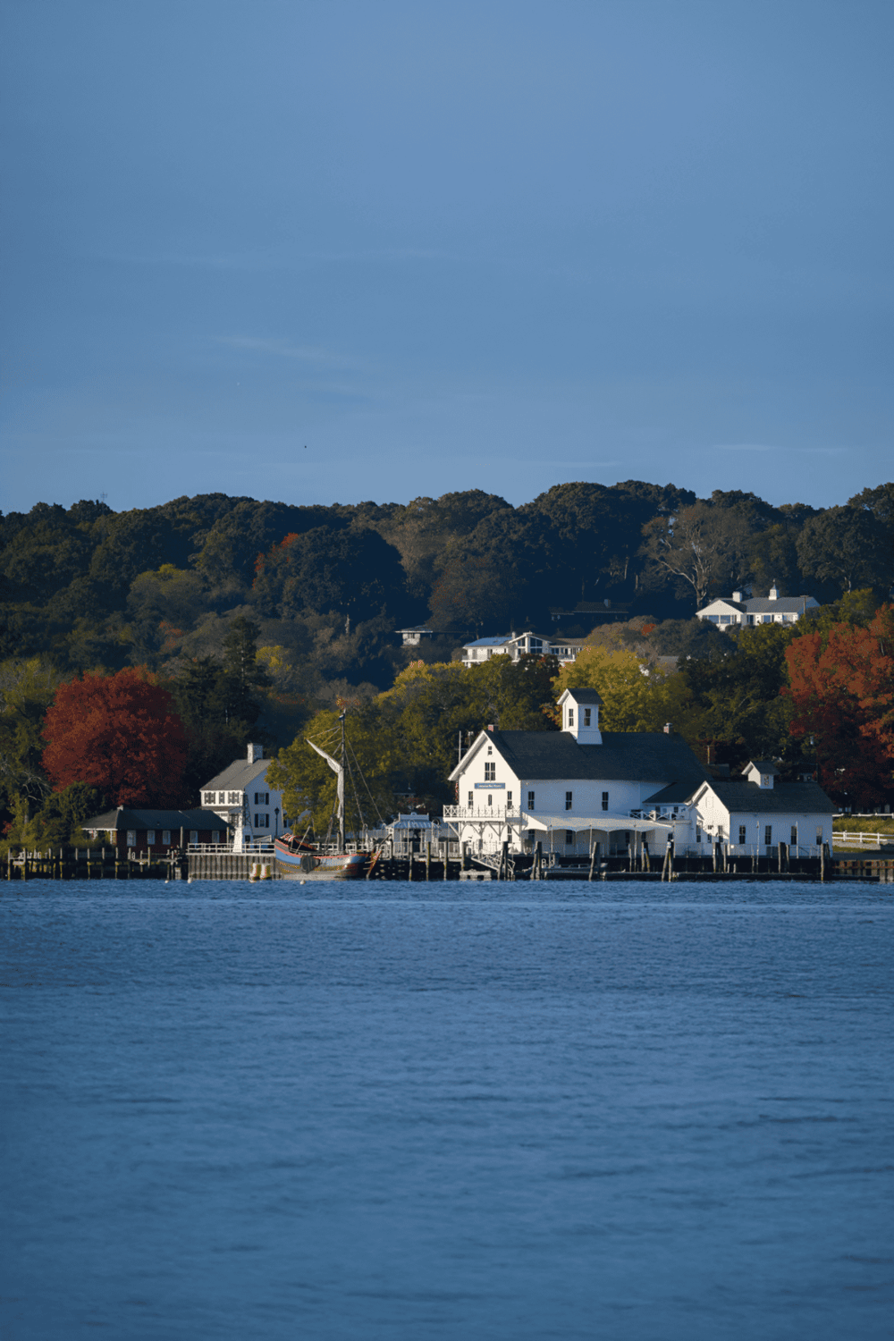 1. Historic waterfront with white buildings and lush fall foliage in the background.