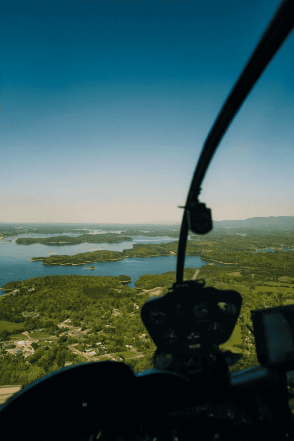 Aerial view of lakes and greenery from helicopter window, scenic flying adventure in nature.