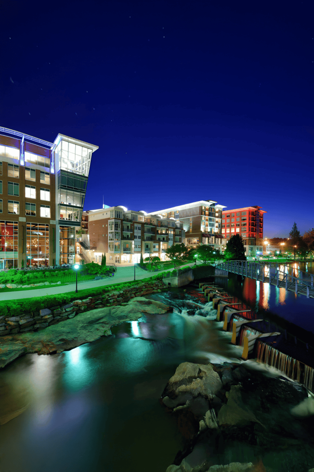 Modern riverside apartment complex illuminated at night, showcasing luxury living near scenic water views.