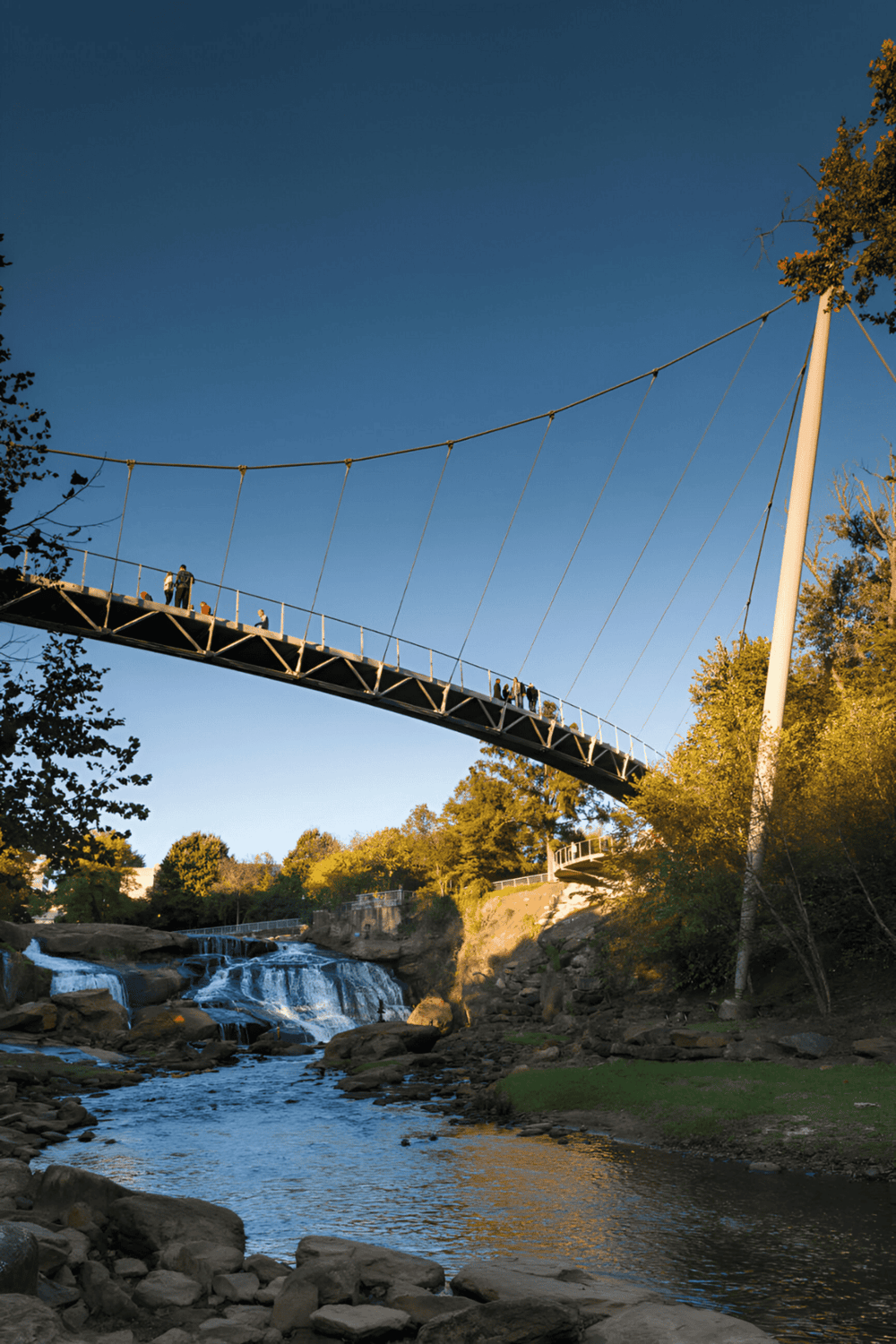 Suspension bridge over waterfall at QuestForDirections park, scenic outdoor adventure destination.