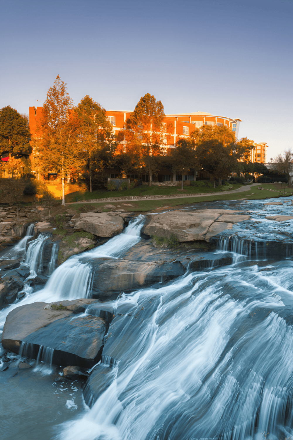 Waterfall near QuestForDirections professional building in downtown, scenic view in warm sunset lighting.