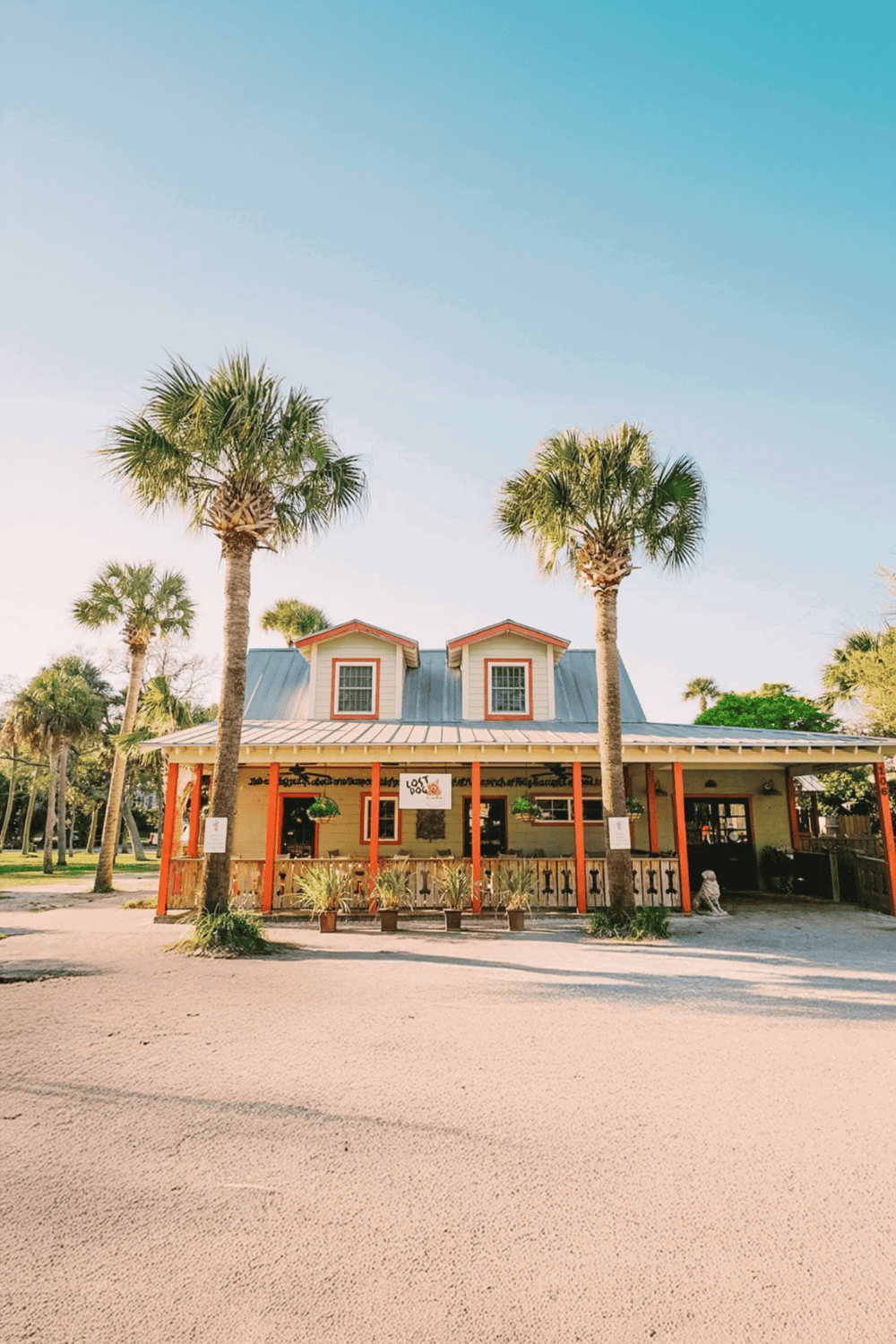 Coastal restaurant with tropical palm trees, outdoor seating, and inviting atmosphere.