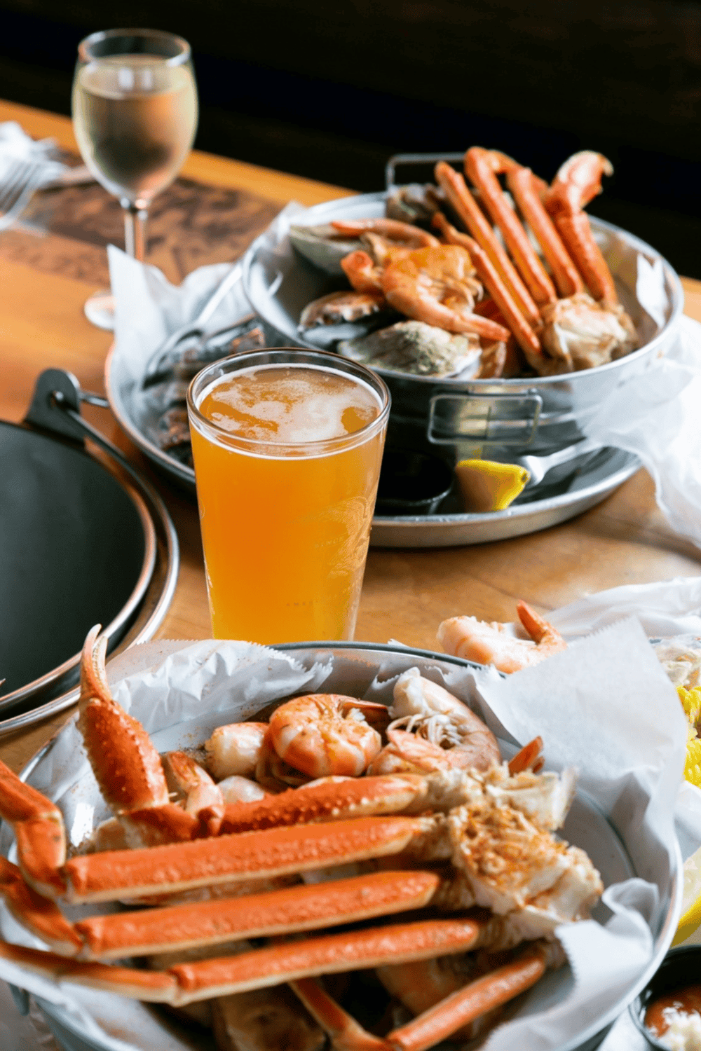 Succulent seafood platter with crab legs, shrimp, and lobster served with cold beer and white wine.