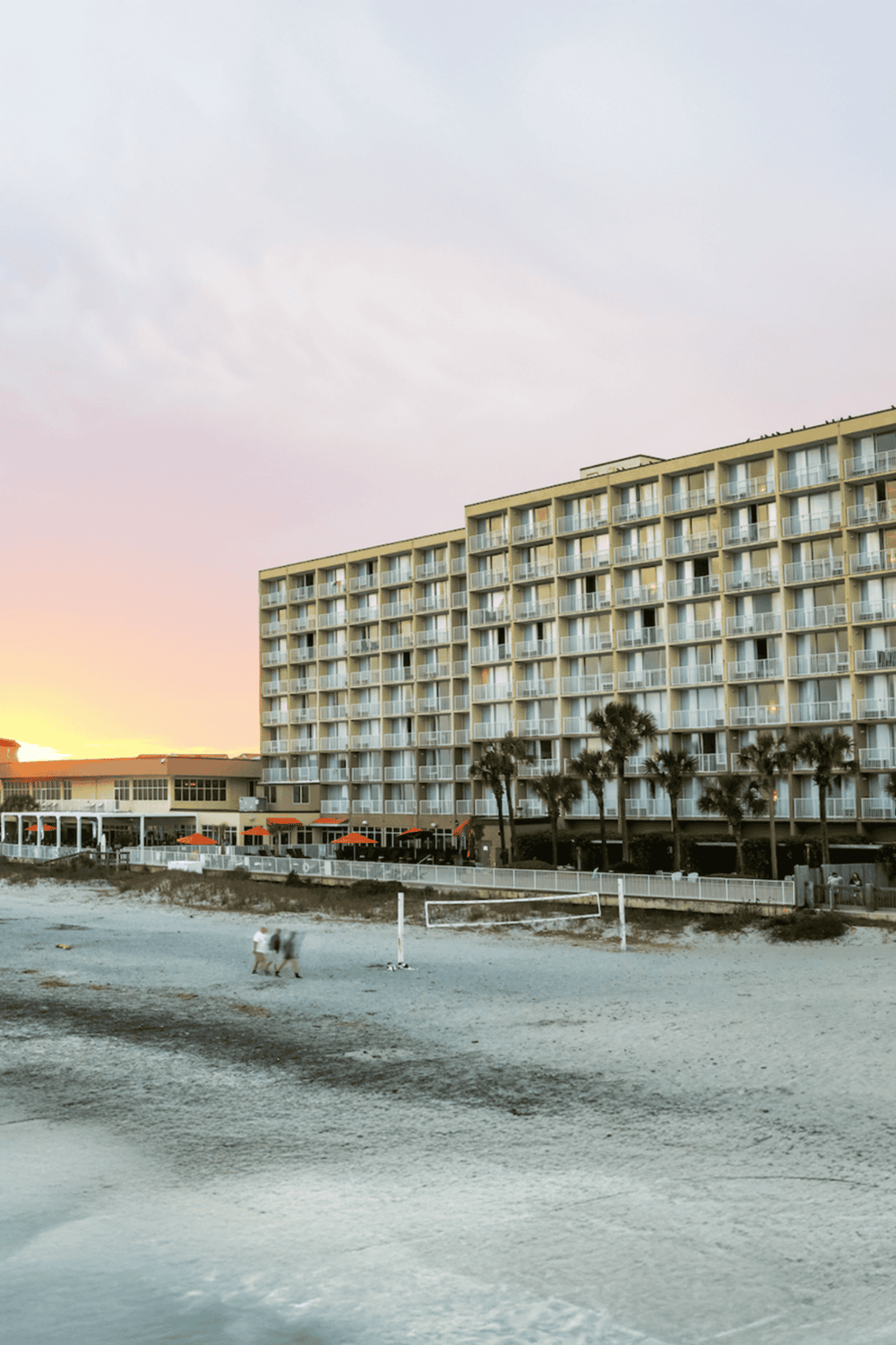 Beachfront hotel with ocean views and nearby volleyball court, perfect for vacation relaxation.