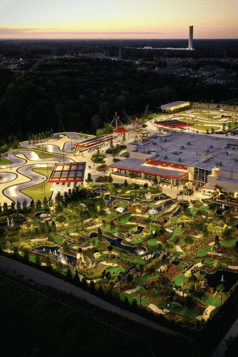Amusement park aerial view at sunset with mini-golf, rides, and lush landscaping in a family-friendly entertainment venue.